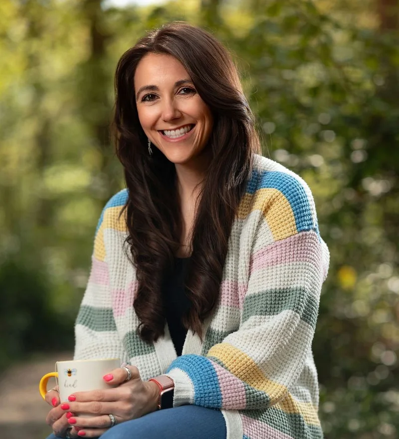 A smiling woman in a striped cardigan holding a mug, outdoor portrait photography by Kombu