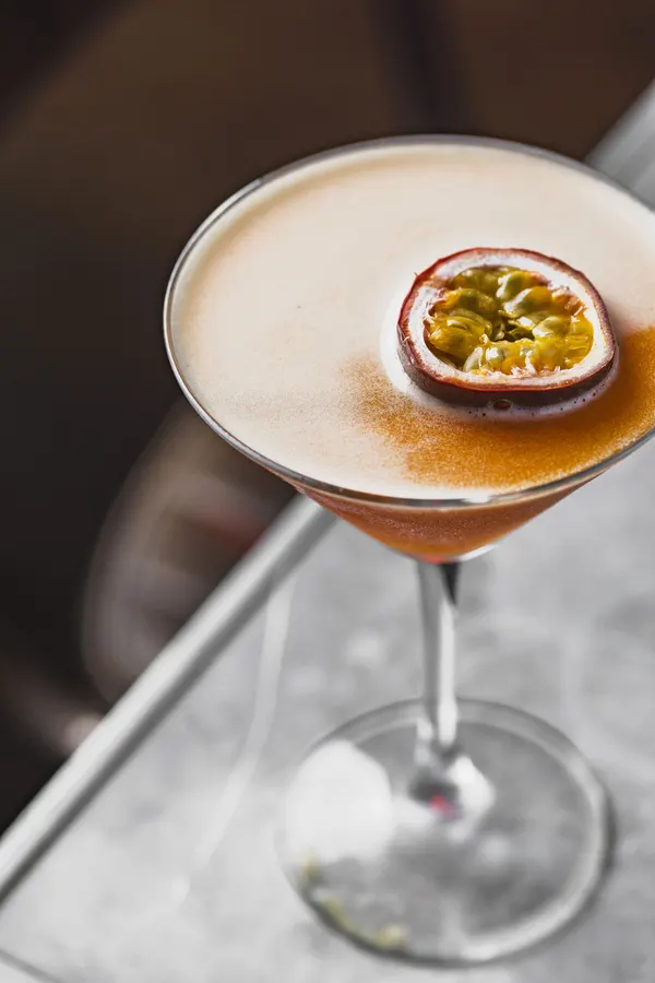 A passion fruit martini on a concrete table