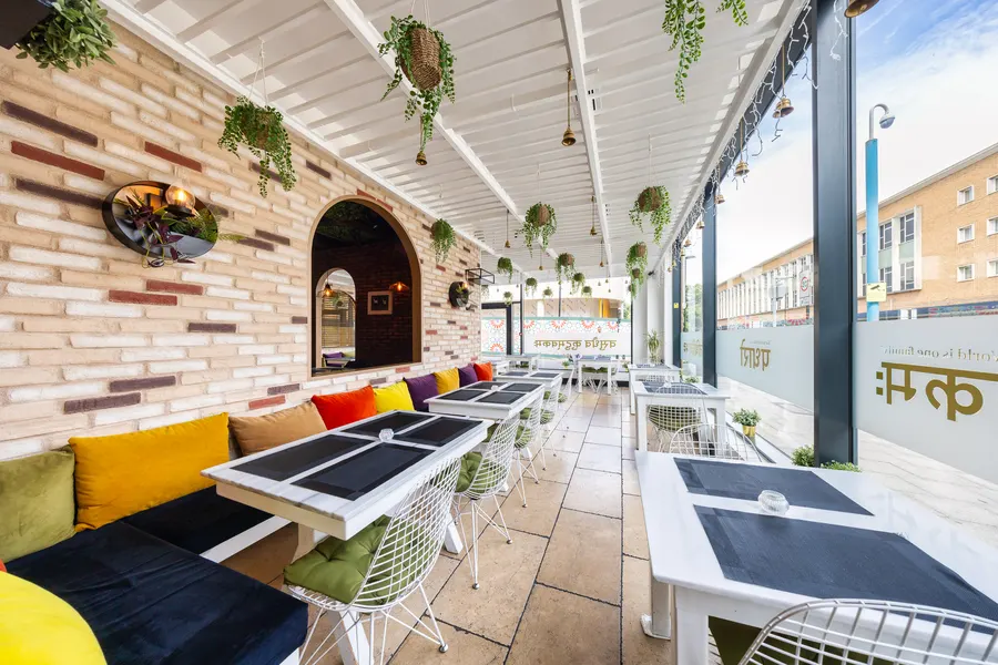 The bright side room with bench seating, cushions and hanging plants
